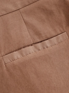 Detailed close-up of pocket stitching and smooth woven fabric texture on tan blazer