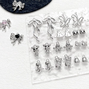 Makro-Detail von silbernen Metallanhängern wie Schleife und Tierformen für DIY-Schmuck