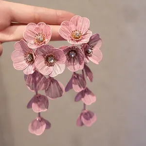Macro detail of pink flower earrings with woven wire petals and crystal center