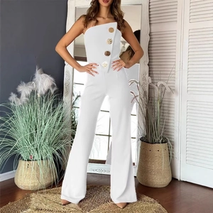 White strapless wide leg jumpsuit with gold buttons in a minimalist interior setting