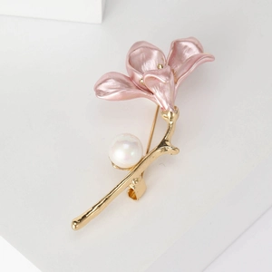 Close-up of pink enamel trumpet flower brooch with gold stem and pearl accents