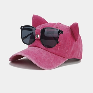 Pink baseball cap with cat ears and aviator sunglasses detail on a clean background
