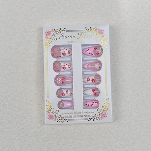 Close-up of pink press-on nails with red lips, bows and rhinestones in gift box
