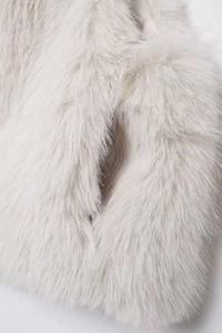 Close-up detail of soft white faux fur material showing dense and glossy texture on a vest