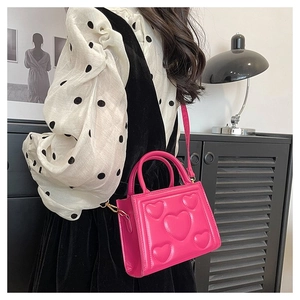 Vue détaillée du sac à main magenta avec gaufrage en cœur 3D et fini brillant sur modèle