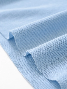 Dettaglio del maglione in maglia azzurro che mostra la trama fine e le pieghe