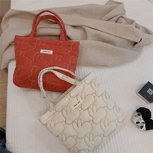 Detailed view of quilted cotton handbags featuring cute rabbit patterns and woven labels