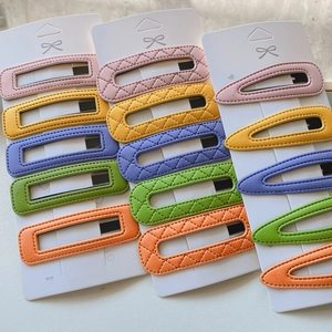 Detailed flat lay of multi-shaped colorful PU leather hair clips on white backing cards