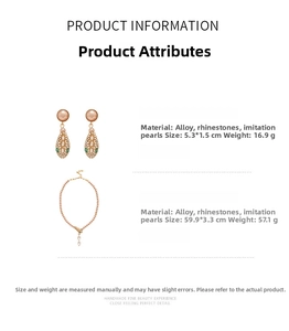 Detail of snake head earrings and pearl necklace with green crystal eyes and gold finish
