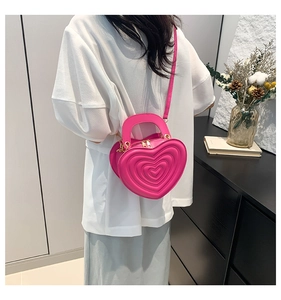 Detailansicht einer herzförmigen gesteppten Handtasche in Pink an einem Modell
