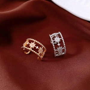 Close-up of double-layer zircon star rings in gold and silver on red silk fabric