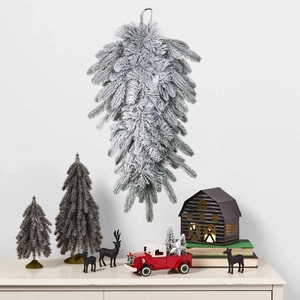 Detail view of snowy white teardrop pine wreath hanging above a festive Christmas cabinet