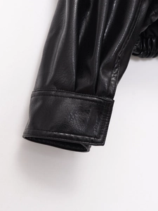 Close-up of cuff stitching on a black faux leather bomber jacket with smooth texture