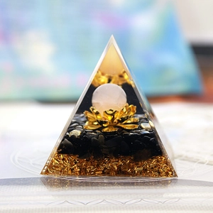 Macro detail of crystal energy pyramid with pink bead on lotus base and black stone layers