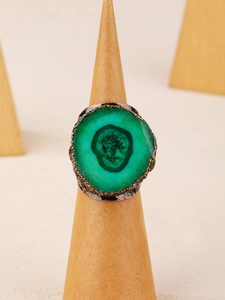 Macro shot of a vintage bronze ring with a green stone featuring a skull-like texture