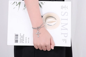 Detail of silver double-layered bracelet featuring a cross pendant and OT toggle clasp