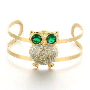 Golden owl cuff bracelet featuring green gemstone eyes and white marble enamel inlay
