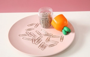 Detailed view of silver paperclips in a round box with a cute orange carrot lid