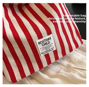 Detailed close-up of red and white striped vintage canvas tote bag texture and logo tag