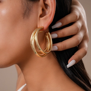Close-up of golden multi-layer geometric C-shaped hoop earrings worn by a model