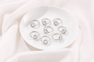 Set di otto anelli geometrici in argento su un piatto di ceramica bianca con seta pura