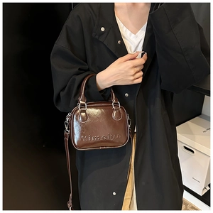 Detail of a brown glossy leather mini square bag with embossed logo on the handbag