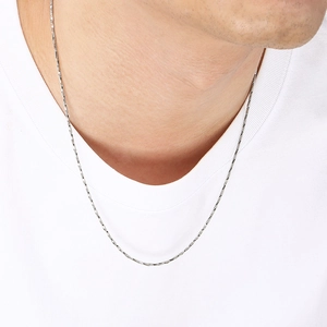 Collier minimaliste en acier inoxydable argenté porté sur un t-shirt blanc propre