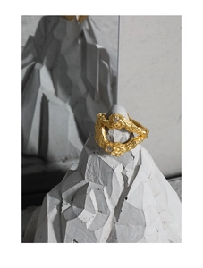 Primo piano artistico di un anello dorato con texture irregolare e zircone su pietra