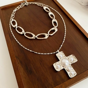 Detail of silver double-layer necklace with large pearl-encrusted cross pendant