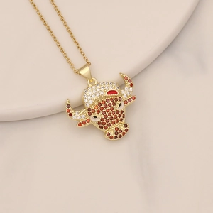 Macro shot of gold bull head pendant with red and white zircon stones on beige ceramic