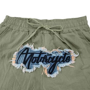 Detail der olivenen Leinenhose mit elastischem Kordelzugbund und Vintage-Stickerei-Patch