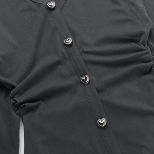 Détail des boutons argentés en forme de cœur sur une robe tricotée gris foncé