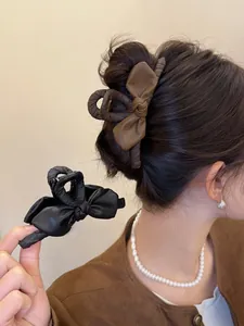 Dettaglio mollette per capelli in pelle con fiocco retrò, stili nero e marrone per donna