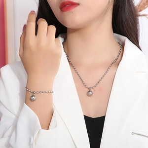 Polished silver beaded necklace and bracelet set with round charms on female model