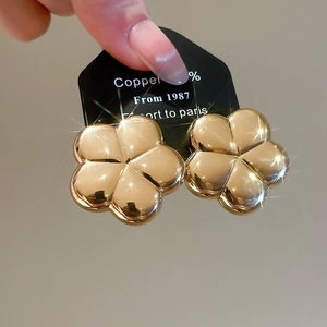 Detail view of glossy 3D five-petal flower stud earrings with a shiny gold finish