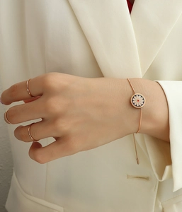 Detail of rose gold daisy snake chain bracelet worn on wrist for a minimalist style
