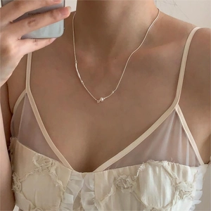 Detailed view of mixed-chain silver necklace with a white pearl and metallic tube on neck