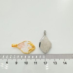 Close-up of irregular 18k gold and silver heart pendants with ruler showing 2.5cm size