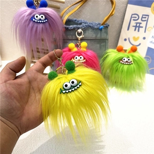 Colorful plush monster keychains with fuzzy fur, large eyes, and jagged teeth on a bag