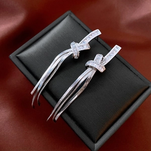 Detail of silver knot tassel earrings with zircon stones on a dark textured display