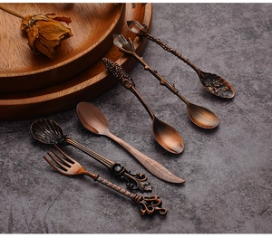 Close-up of vintage bronze carved dessert spoons and fork set with ornate handle details