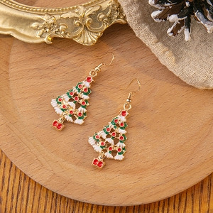 Detailed top view of Christmas tree earrings on a wooden tray with festive decorations