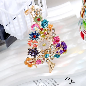 Detailed close-up of a Christmas tree brooch with colorful rhinestones and enamel flowers
