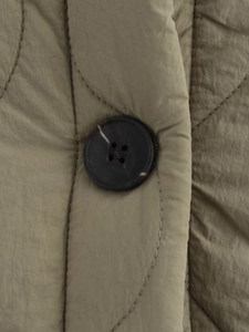 Macro detail of khaki olive quilted jacket fabric texture and resin button closure