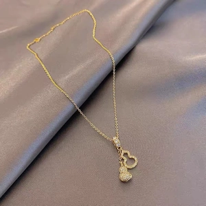 Macro shot of gold gourd pendant with micro-pave diamonds on elegant silk fabric