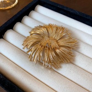 Macro detail of a vintage golden floral brooch presented in a soft velvet jewelry gift box
