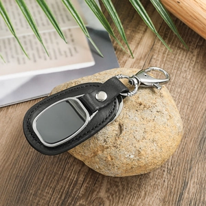 Detail of premium black leather keychain with silver metal hook on natural wooden background