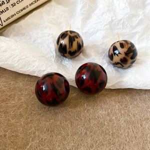 Macro detail of round leopard print resin earrings with elegant gold posts for daily wear