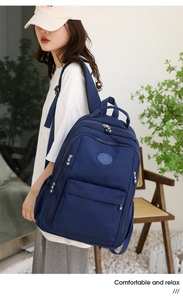 Detail of dark blue multi-compartment nylon backpack showing side view on a model