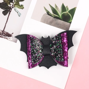 Close-up of Halloween bat hair bow with purple sequins on a decorative white display card